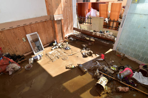 flooded room with muddy water scattered items and damaged furniture and walls