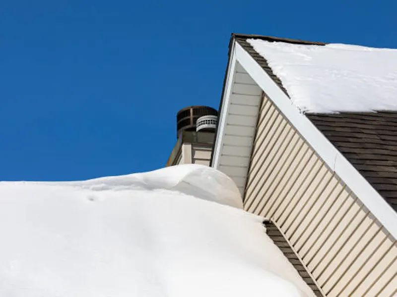 house with ice dam forming on roof edge against a clear blue sky