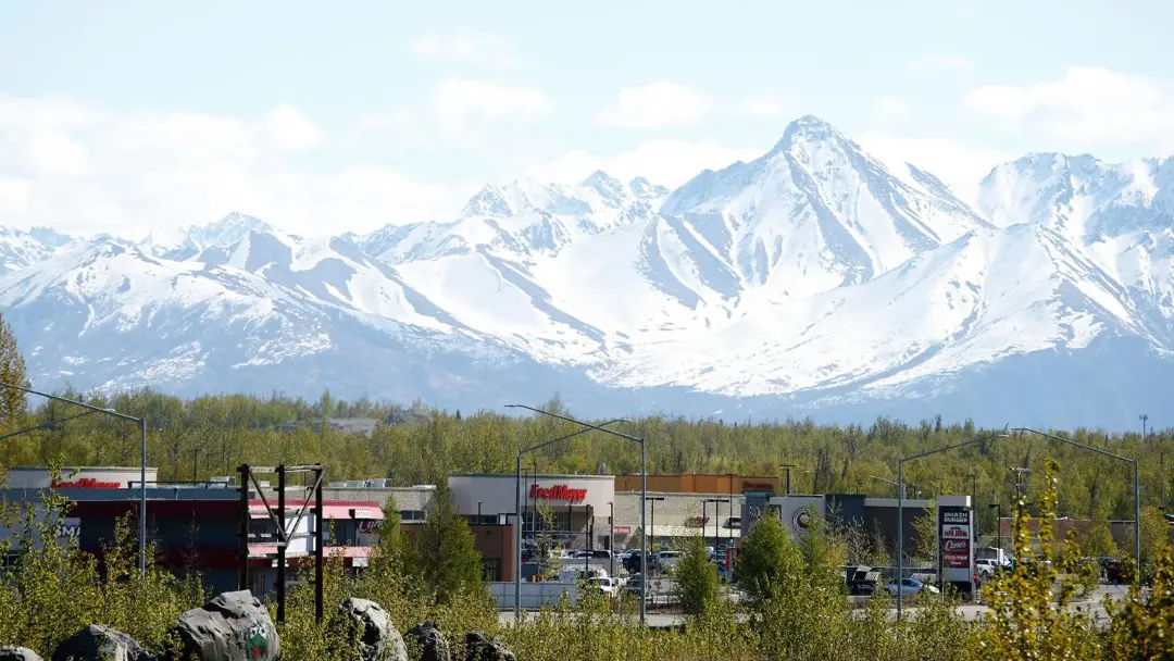 snowy mountains behind wasilla ak with city buildings in the foreground