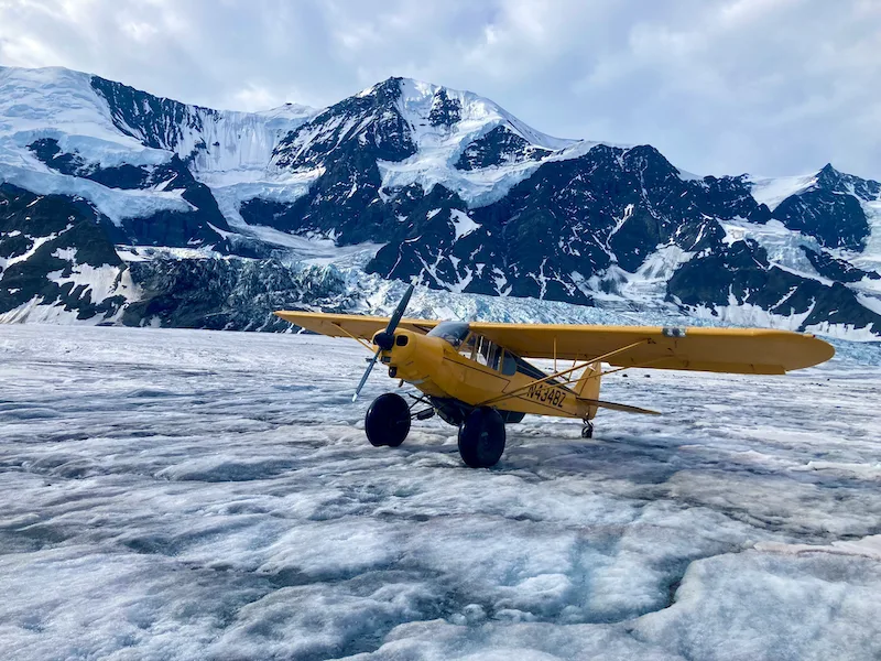 yellow airplane on snow in alaska representing arctic restoration cleaning